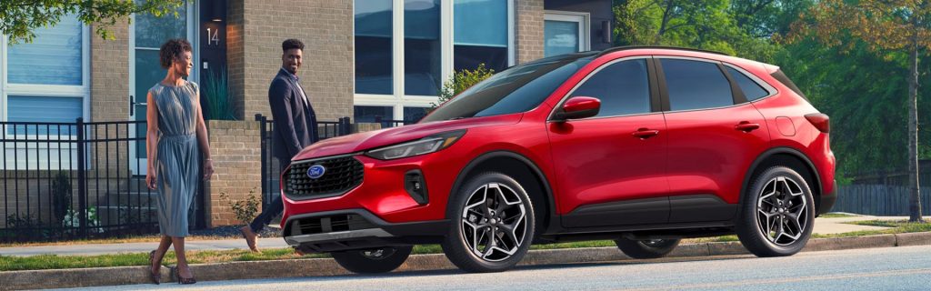 A Red 2026 Ford Escape SUV parked on a residential street as two people walk past a modern home.