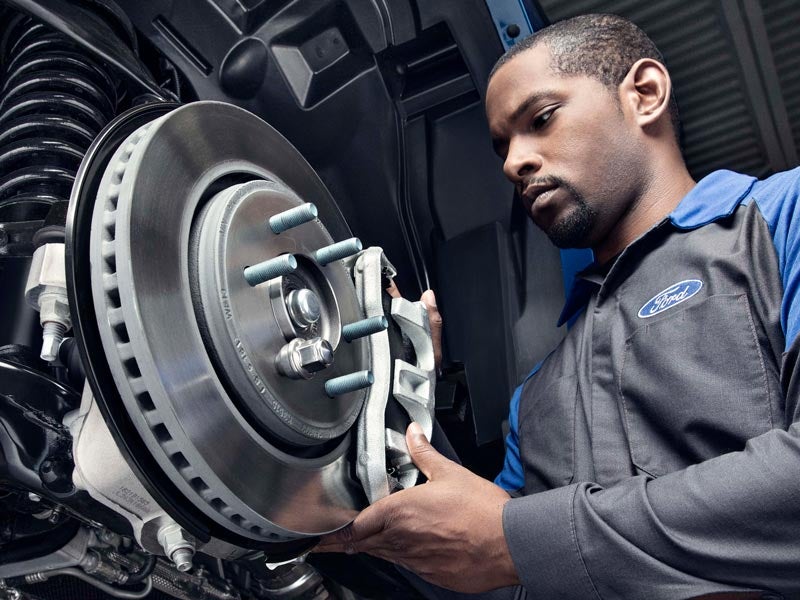 A Ford service Technician working on a vehicle brakes