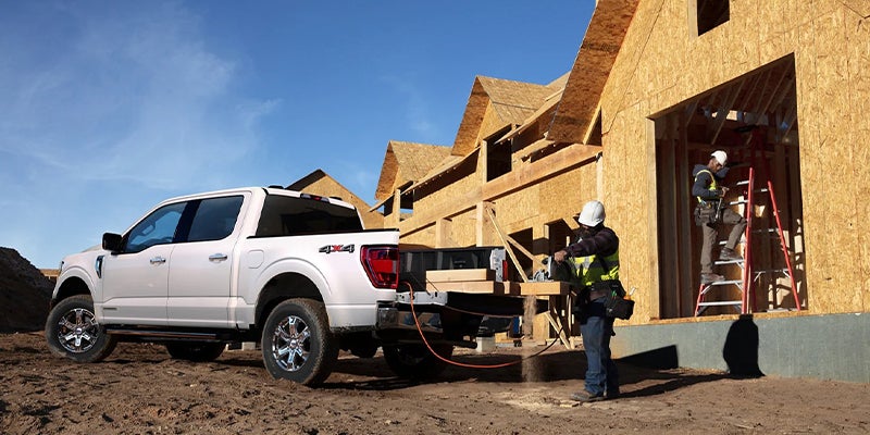 Ford truck at a construction site with workers building wooden houses