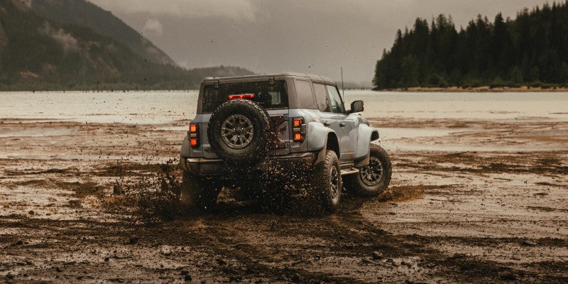 A grey Ford Bronco driving on a desert terrain