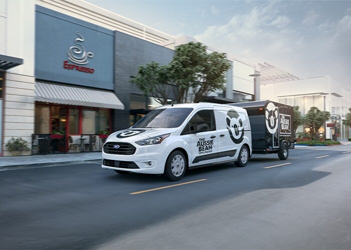Am Aussie Bean branded Ford vehicle driving next to a coffee site while pulling a trailer