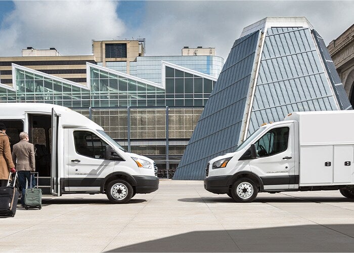 Two Ford Commercial vehicles parked in front of a futuristic looking building