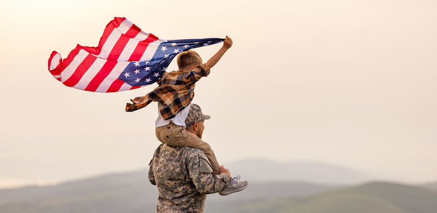Military man carrying boy on shoulder 