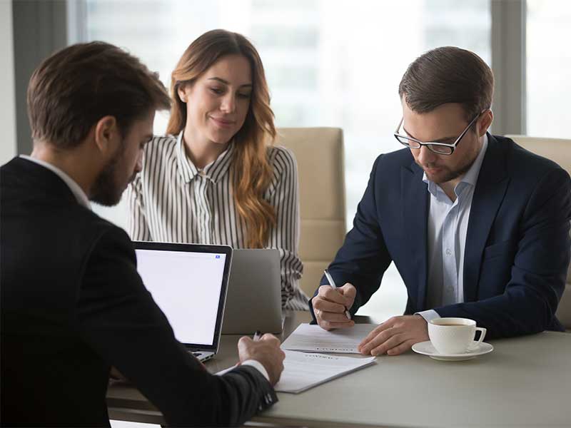 A couple, inside an agent office, signing some papers